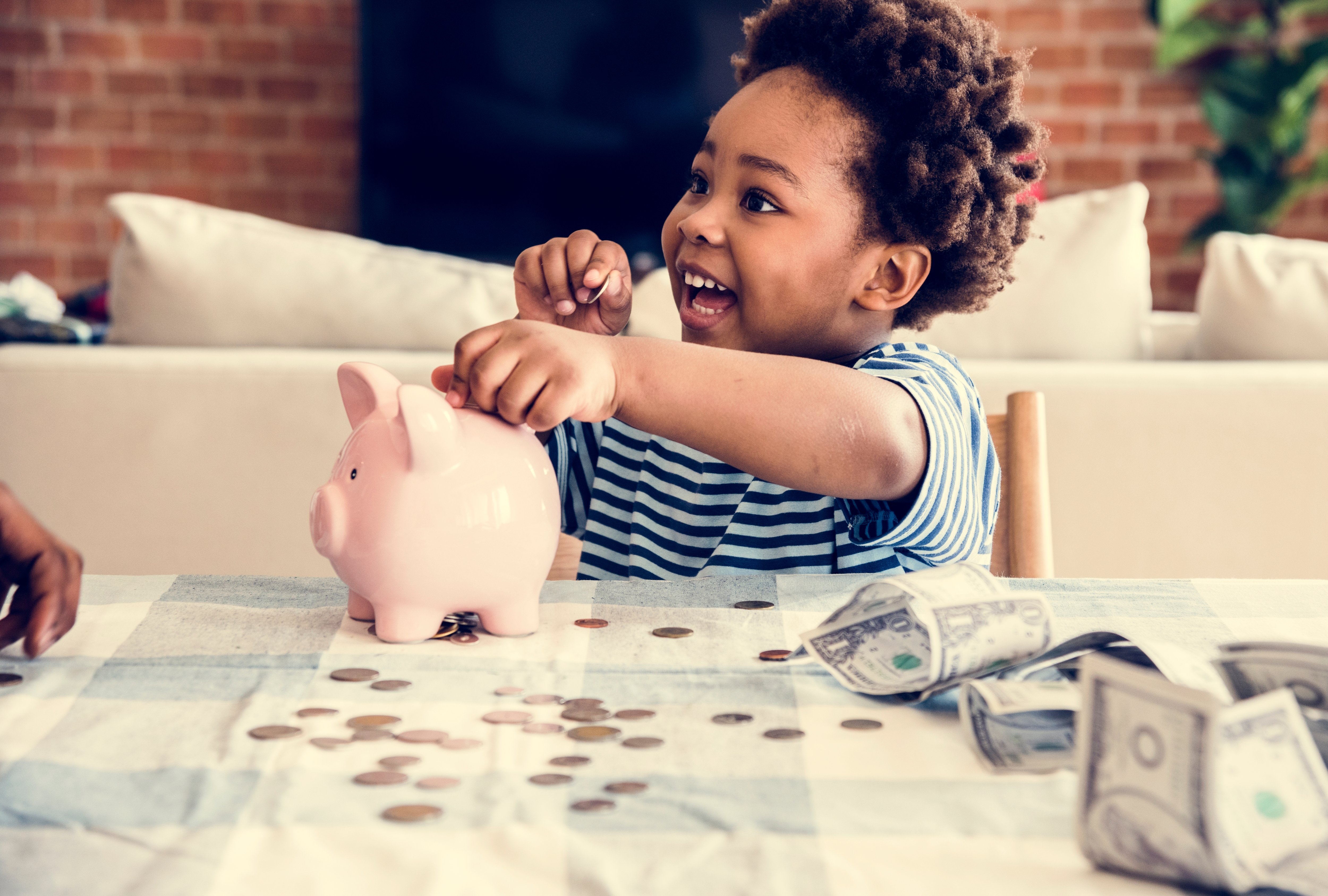 A young child putting money into a piggy bank