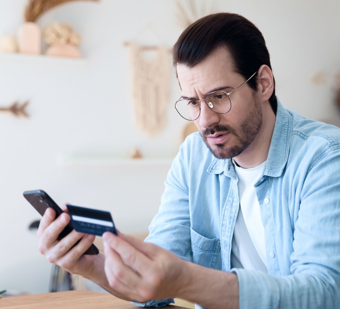 man looking at phone and credit card