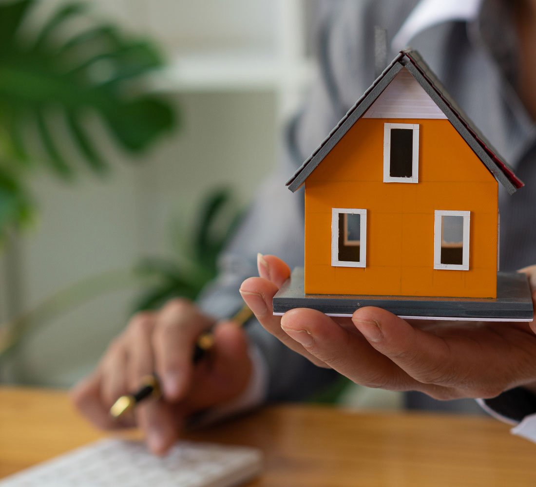 person holding replica of a house