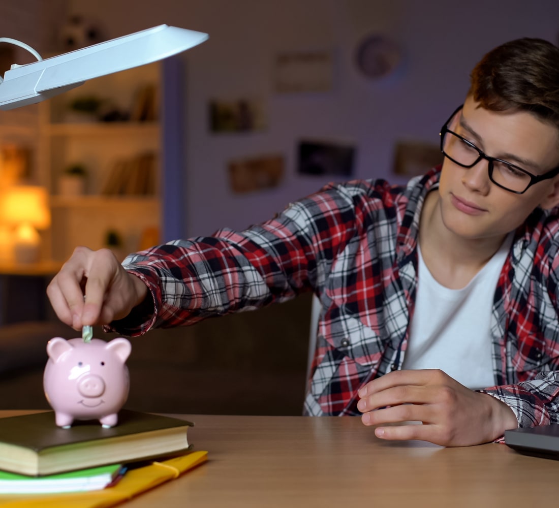 young boy putting coin in piggy bank