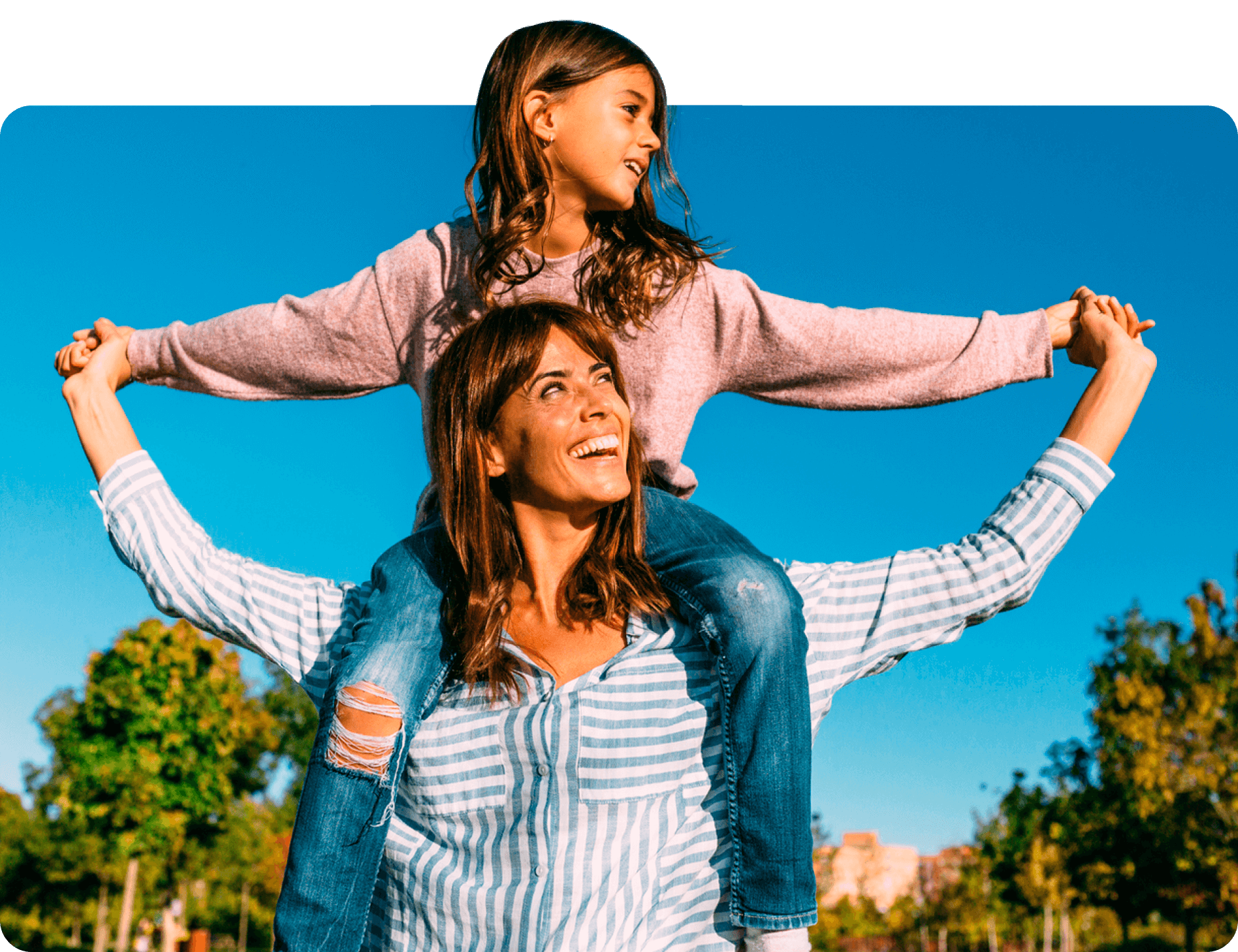 A woman with her child sitting on her shoulders outdoors